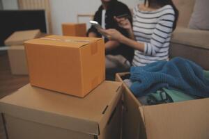 Two Asian blogger showing clothes in front of the camera to recording vlog video live streaming at her shop. Online Shopping Cart notion. on sofa at home photo
