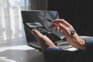 businessman working on desk office with using a calculator to calculate the numbers, finance accounting concept photo