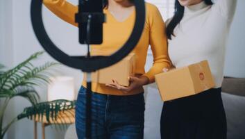 asiático mujer amigos Pareja hablar a cámara a vender el ropa a hogar. joven atractivo negocio personas hembra En Vivo transmisión y demostración ropa a cliente en en línea Al por menor a ventas a oficina Tienda foto