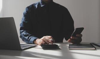 businessman working on desk office with using a calculator to calculate the numbers, finance accounting concept photo
