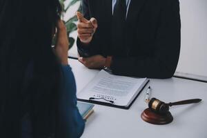 Justice and Law concept. Legal counsel presents to the client a signed contract with gavel and legal law or legal having team meeting at law firm in background photo