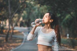 A health-conscious woman takes a refreshing break to drink water during her outdoor exercise routine, highlighting the importance of hydration in fitness. photo