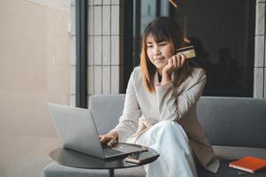 mujer joven con tarjeta de crédito y usando computadora portátil. empresaria trabajando en casa. compras en línea, comercio electrónico, banca por Internet, gastar dinero, trabajar desde el concepto de hogar foto