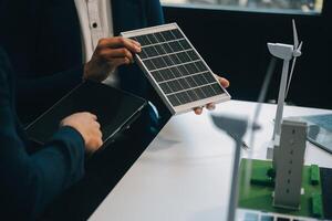 dos joven ingenieros pericia en solar célula instalación reuniones y discusión en el trabajo. planificación a Instalar en pc solar fotovoltaica paneles en techo parte superior en el oficina habitación con fábrica edificio plan. foto