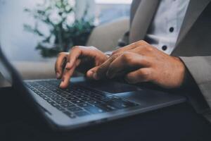 Young businessman working in office, sitting at desk, looking at laptop computer screen photo