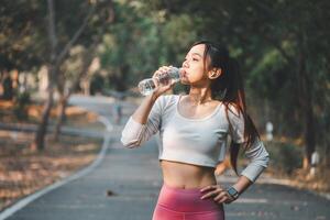 A health-conscious woman takes a refreshing break to drink water during her outdoor exercise routine, highlighting the importance of hydration in fitness. photo