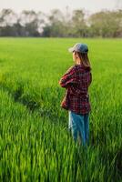 Side view of a pensive female farmer standing amidst a sea of green rice plants, reflecting on the growth of her crops. photo