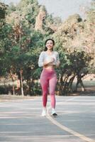 A joyful runner wearing pink leggings and white sneakers exudes happiness and health while jogging on a park path, surrounded by greenery. photo