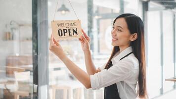 Young entrepreneur holding open sign on glass door at cafe photo