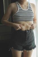 mujer cuerpo grasa barriga. obeso mujer mano participación excesivo barriga gordo. dieta estilo de vida concepto a reducir barriga y forma arriba sano estómago músculo. foto