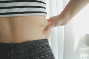 Women body fat belly. Obese woman hand holding excessive belly fat. diet lifestyle concept to reduce belly and shape up healthy stomach muscle. photo