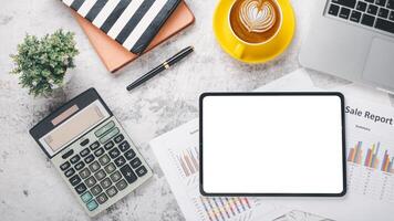 Overhead view of a well-organized desk featuring a digital tablet with a blank screen, financial reports, a calculator, and a cup of coffee, symbolizing strategic business planning and analysis. photo