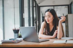 A young freelancer concentrates on her laptop screen, immersed in her work at a wooden desk in a bright home office, a portrait of dedication and modern entrepreneurship. photo