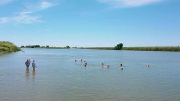 Antenne Drohne Aussicht von ein festgemacht Boot in der Nähe von das Küste von Fluss. Frauen Schwimmen im Fluss und transparent Wasser. Alten Tourismus video