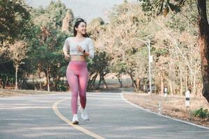 A joyful runner wearing pink leggings and white sneakers exudes happiness and health while jogging on a park path, surrounded by greenery. photo