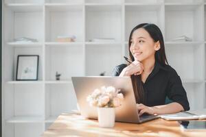 A smiling professional woman is fully engaged with her laptop in a minimalist and bright office space, reflecting the modern simplicity of today's work environment. photo