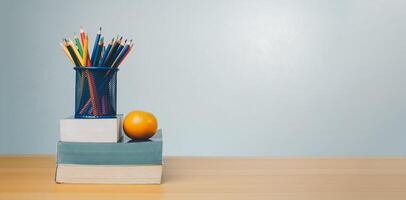 Stack of colorful textbooks and a glass of bright pencils on a white background, Concept of education, training, School tools, workspace, copy space, Banner design education concept background. photo