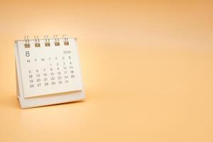 Simple desk calendar for August 2024 isolated on orange background. Calendar concept with copy space. photo