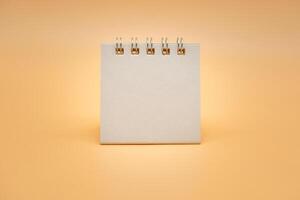 Blank calendar isolated on orange background. Blank paper desk spiral calendar. close up of a blank recycle paper template. photo