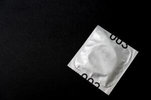 Condom isolated on black background. Copy space for text. Sex protection, safe sex concept. Prevent infection. photo