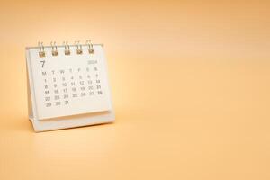 Simple desk calendar for July 2024 isolated on orange background. Calendar concept with copy space. photo