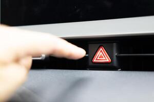 presses the emergency stop button in the car. Car emergency warning light button in front car console photo