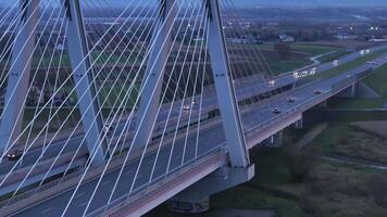 aéreo ver tráfico Moviente en el puente a oscuridad en el ciudad de Cracovia en Polonia. de cerca de un moderno atirantado puente intrincado arquitectura en contra el fondo de un crepúsculo cielo en Cracovia. video