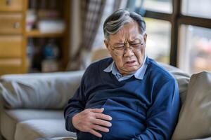 AI generated Asian senior man suffering from abdominal pain. photo