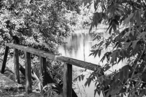 Beautifully standing old wooden bridge over river in light background photo