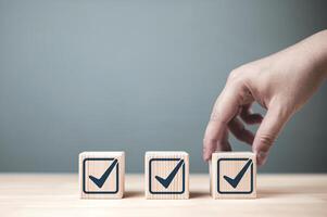 Inspection and certification of standards. Check mark on wooden block. Concept of item verification, jobs list, and product quality certification. photo