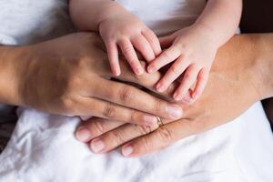 Close-up of newborn hands placed on hands mother and father. Happiness parents. Love of family concept. Space for text photo
