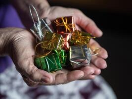 Close-up of colorful small gift boxes in the hands of a senior woman. Concept of aged people and festival photo