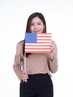 joven mujer participación el nosotros bandera, sonriente y mirando a el cámara con un blanco antecedentes. espacio para texto. 4to de julio. celebrar americano nacional día. labor día. independencia día foto