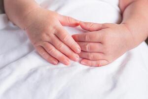 Hands of a newborn baby on white cloth with copy space. Close-up of baby hands. Family concept photo