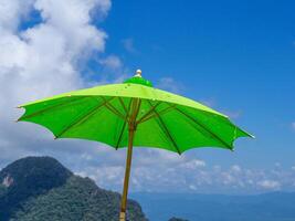 Close-up of a green big umbrella on beautiful blue sky and mountain background photo