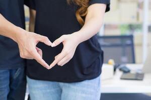 Close-up of a young couple making a heart shape with hands. Space for text. Concept of celebrating Valentine's Day photo