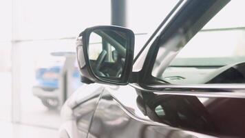 Unfolding the outside rearview mirror with built-in turn signal light on a prestigious brown car in a dealer showroom video