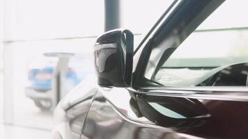 Folding the outside rearview mirror with built-in turn signal light on a prestigious brown electric car in a dealer showroom video