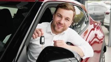 il uomo con chiavi Spettacoli emozioni di felicità mentre guida nel sua nuovo macchina. il acquirente seleziona un' auto video