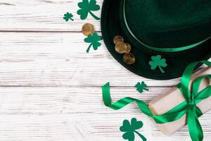 Background for St. Patrick's Day. Leprechaun hat, gold coins and clover shamrock on a white wooden background. Good luck symbols. photo