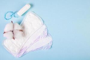 Sanitary pads and tampon on blue background. Feminine menstrual hygiene products. photo