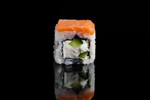rollo de sushi filadelfia sobre fondo negro con reflejo. rollos de uramaki. foto