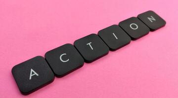 The word Action spelled out in black plastic buttons on a pink background photo