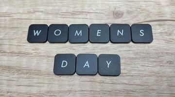 Women's day text on black buttons on wooden background, top view photo