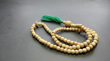 Wooden rosary beads with green thread on black background. photo