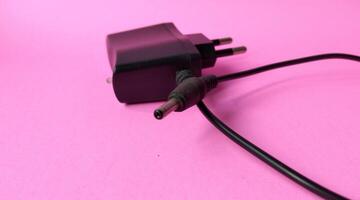 Black power plug on a pink background. Copy space for text. photo