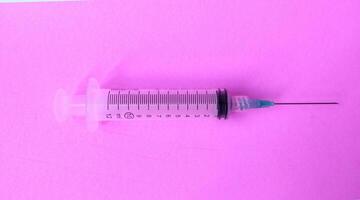 Syringe on a pink background. Close-up. Copy space. photo