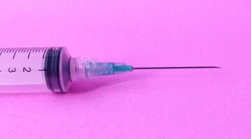 Syringe on a pink background. Close-up. Copy space. photo