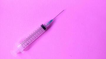 Syringe on a pink background. Close-up. Copy space. photo