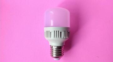 ligero bulbo en un rosado antecedentes. el concepto de ahorro energía. foto